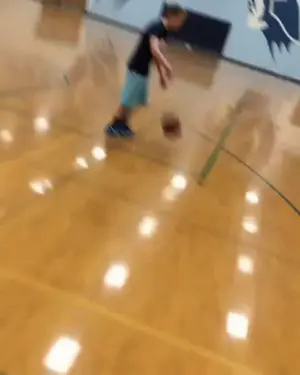 A Man Is Dribbling A Basketball On A Basketball Court While Another Man Tries To Stop Him .