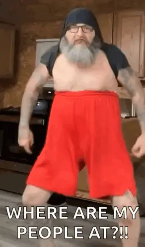 A Man With A Beard Is Dancing In A Kitchen Wearing Red Shorts .