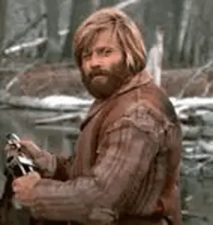 A Man With A Beard And Long Blonde Hair Is Holding A Sword In A Forest .