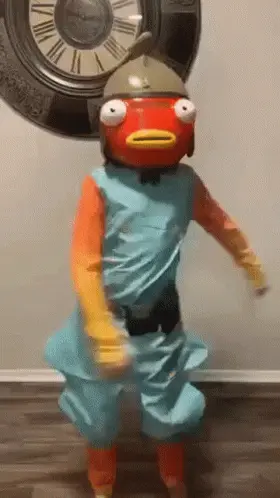A Person In A Fish Costume Is Dancing In Front Of A Large Clock .