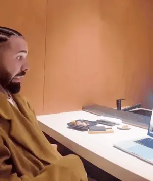 A Man Is Sitting At A Desk Looking At A Laptop Screen