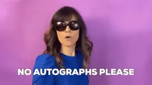 A Woman Wearing Sunglasses And A Blue Shirt Is Making A Funny Face And Saying `` No Autographs Please '' .