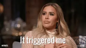 A Woman Sitting On A Couch With The Words It Triggered Me Written On Her Face