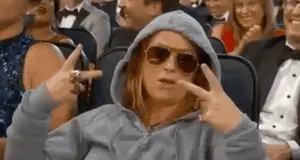 A Woman Wearing A Hoodie And Sunglasses Is Sitting In A Crowd Of People In A Theater .