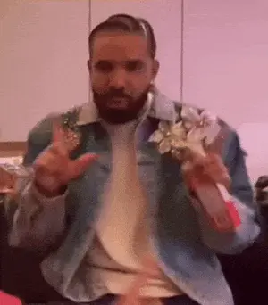 A Man With A Beard Wearing A Denim Jacket Is Holding A Flower In His Hands .
