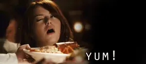 A Woman Sitting At A Table With Her Mouth Open And A Plate Of Food With The Word Yum Written On It
