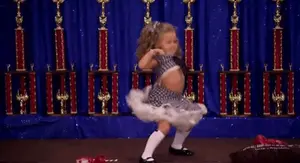 A Little Girl Is Dancing In Front Of Trophies And A Sign That Says ' I Love You ' On It
