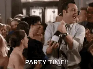 A Man In A Suit And Tie Is Dancing In A Crowd Of People At A Party And Holding A Microphone .