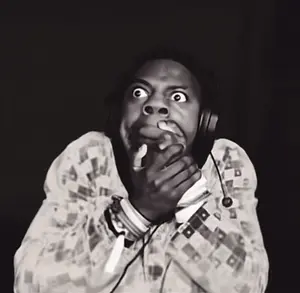 A Person Wearing Headphones Covering Their Mouth With Their Hand