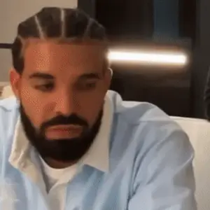 A Man With A Beard And Braids Is Sitting On A Couch And Looking At The Camera .