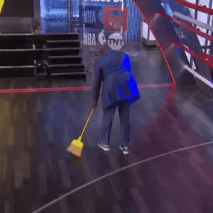 A Man In A Suit Is Sweeping The Floor In Front Of A Sign That Says Nba On It