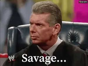 A Man In A Suit And Tie Is Sitting In A Chair With The Words Savage Written Below Him