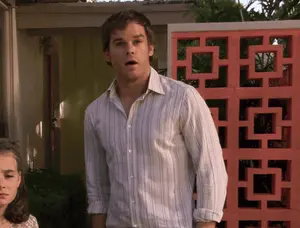 A Man In A White Striped Shirt Is Standing In Front Of A Pink Block Wall
