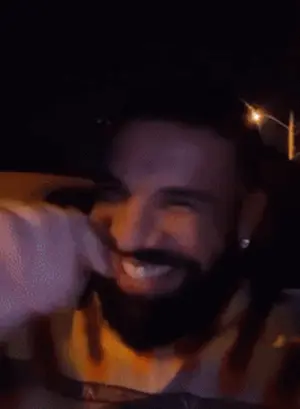A Man With A Beard Is Smiling In A Car At Night