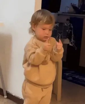 A Little Boy Wearing A Tan Sweater With A Bear On It