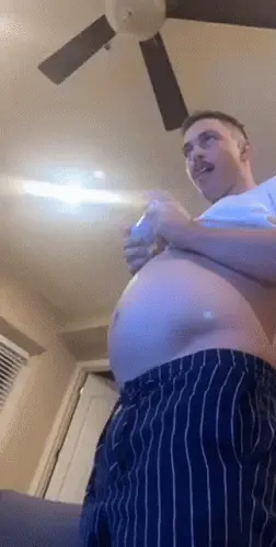 A Man With A Very Large Belly Is Playing A Video Game With A Remote Control .